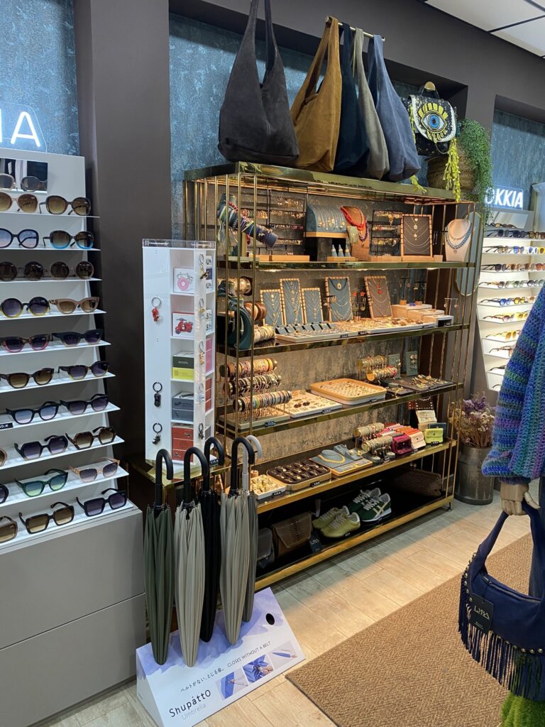 Bisutería, bolsos de ante y paraguas Shupatto en LYBA Store Estantería de LYBA Store con collares, pulseras, anillos, bolsos de ante, llaveros y paraguas Shupatto