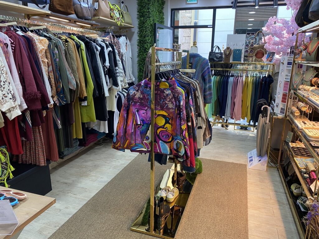 Interior de LYBA Store con chaquetas estampadas, sudaderas de colores, bisutería y paraguas