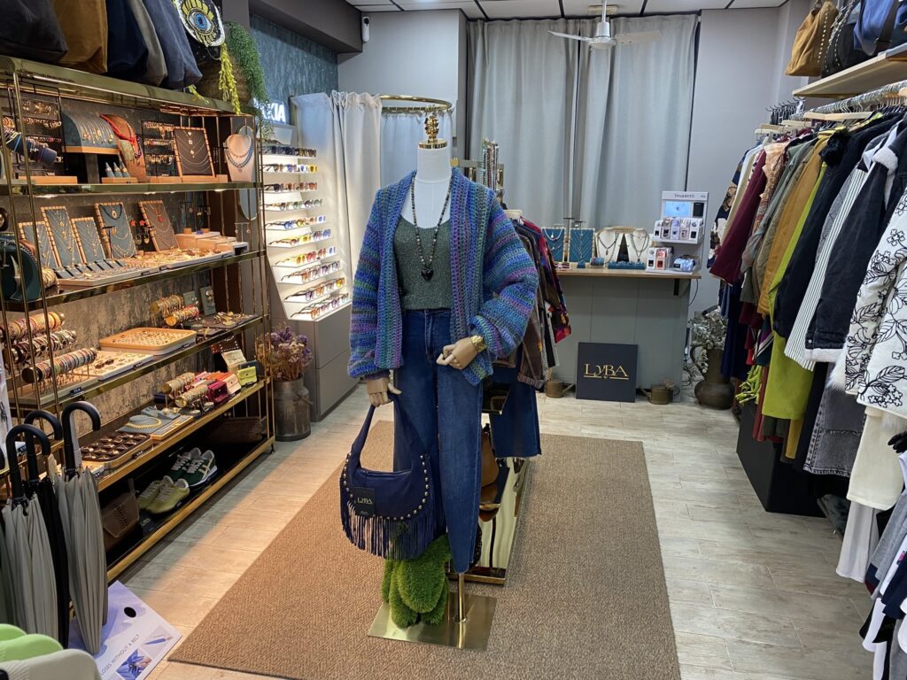Interior de LYBA Store en Valencia con maniquí con chaqueta de punto, joyería, gafas OKKIA y burros de ropa