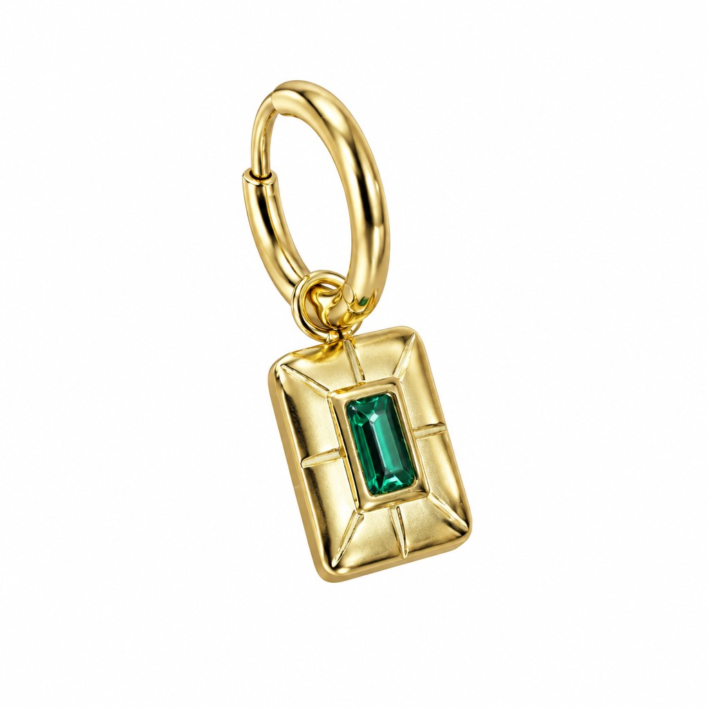 Detalle de un pendiente dorado con placa rectangular y cristal verde talla baguette